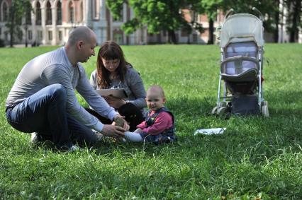 МОсква. Женщина и мужчина  с ребенком на лужайке  в  парке `Музея-заповедника Царицыно`.