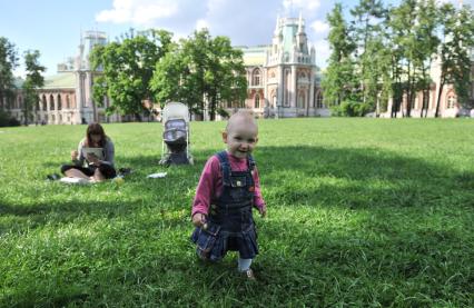 МОсква. Женщина с ребенком на лужайке  в  парке `Музея-заповедника Царицыно`на фоне дворца .