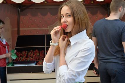 Москва.   Девушка ест клубнику.