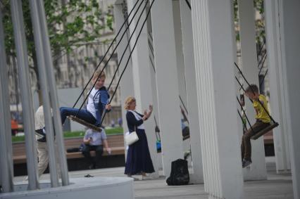 Москва. Мальчик качается на качелях на Триумфальной площади.