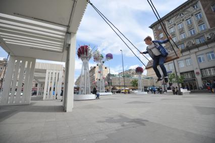 Москва. Мальчик качается на качелях на Триумфальной площади.