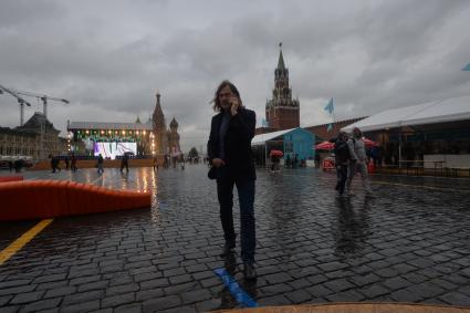 Москва. Художник Никас Сафронов под дождем  на книжном фестивале `Красная площадь` говорит по мобильному телефону.