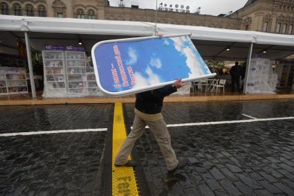 Москва. Мужчина укрылся от дождя рекламным щитом на книжном фестивале `Красная площадь`.