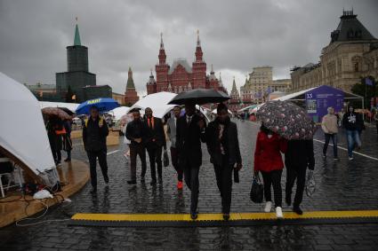 Москва. Прохожие  под зонтами на книжном фестивале `Красная площадь`.