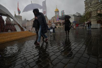 Москва. Прохожие  под зонтами на книжном фестивале `Красная площадь`.