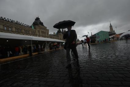 Москва. Прохожие  под зонтами на книжном фестивале `Красная площадь`.