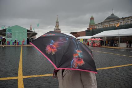 Москва. Женщина под зонтом на книжном фестивале `Красная площадь`.
