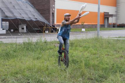 Нижний Новгород. Фестиваль жонглеов. Мужчина  балансирует на одном колесе и жонглирует булавами.