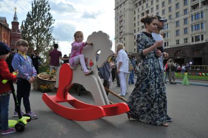 Москва. Девочка качается на деревянной лошадке на историко-гастрономическом фестивале `Наш продукт` в рамках уличных праздников `Московские сезоны` на Площади Революции.