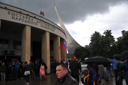 Москва. Прохожие прячутся от дождя под навесом станции метро ВДНХ.