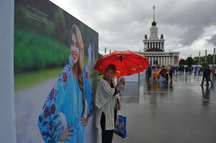 Москва.   Женщина под зонтом на   центральной аллее ВДНХ ,где открылась  фотовыставка  `Многонациональная Россия`.