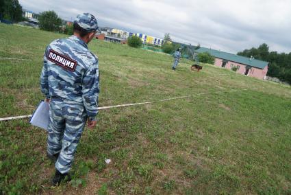 Екатеринбург. Судья наблюдает как полицейский-кинолог с своей служебной собакой выполняют задание на областных соревнованиях кинологов МВД и Таможни