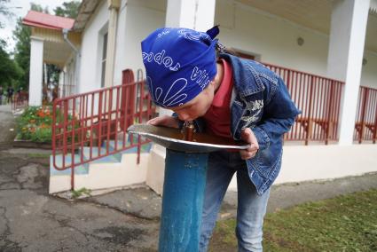 Свердловская область. Девочка пьет воду из питьевого фонтана в детском летнем оздоровительном лагере.