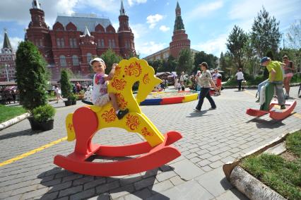 Москва.   Мальчик качается на деревянной лошадке на Манежной площади, где проходит фестиваль `Московское мороженое`.