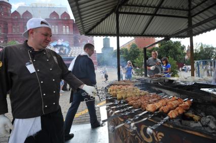 Москва.   Мужчина жарит шашлык на Манежной площади.