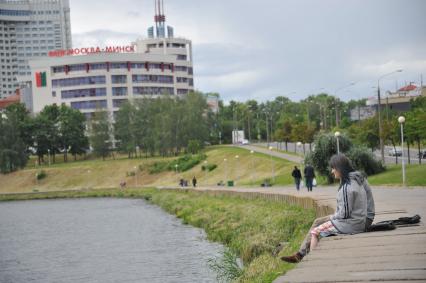 Белоруссия.  Минск. Женщина сидит на берегу реки.