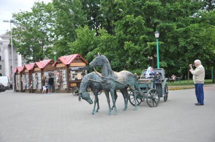 Белоруссия.  Минск. Мужчина фотографирует памятник `Карета губернатора  Захария Корнеева`.