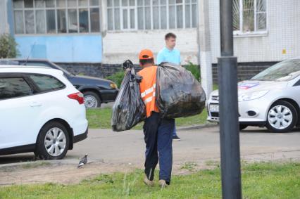 Москва, п. Щербинка. Дворние несет пакеты с мусором.