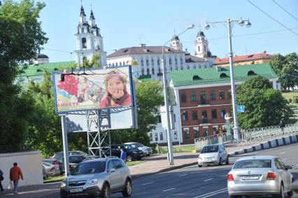 Белоруссия. Минск. Билборд на улице города на фоне Кафедрального собора Сошествия Святого Духа.
