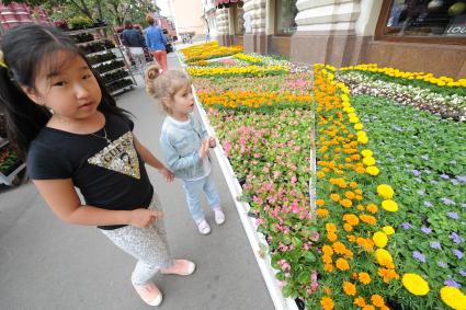 Москва.  Девочки любуются на  цветочный ковер на Красной площади во время проведения фестиваля цветов в ГУМе.