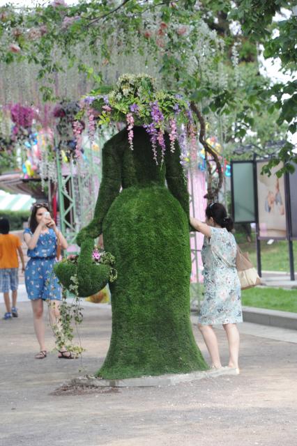 Москва.  Девушки фотографируются у скульптуры из живых цветов на бульваре.