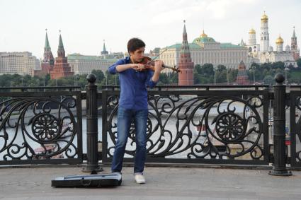 Москва.  Скрипач играет на Патриаршем мосту.