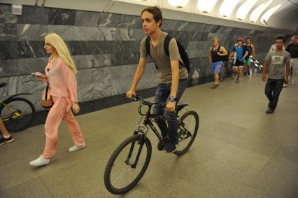 Москва.  Молодой человек едет на велосипеде по платформе станции метро.