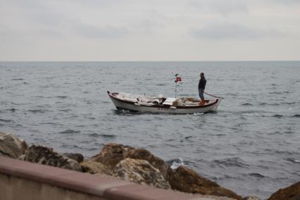 Турция. Мужчина плывет на лодке с турецким флагом.