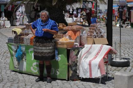 Португалия. Назаре.  Женщина торгует сухофруктами.