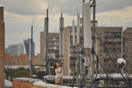 Москва. Девушка стоит возле базовой станции мобильной связи, установленной на крыше офисного здания.