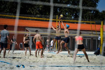 Москва. Молодые люди играют в пляжный волейбол.