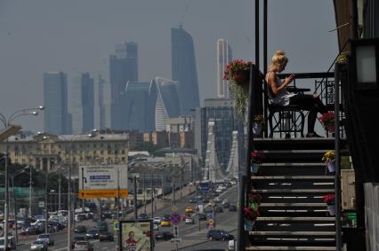 Москва.  Девушка на балконе среди цветов.