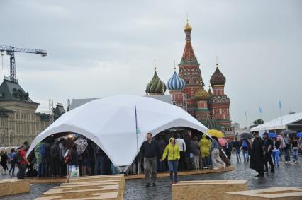 Москва. Посетители спрятались под тент во время дождя на книжном фестивале `Красная площадь`.