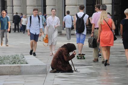 Москва. Женщина просит милостыню у прохожих на Тверской улице.