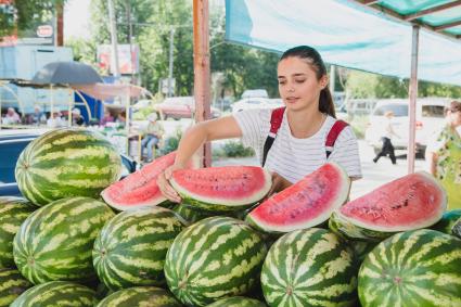 Челябинск. Девушка выбирает арбуз на рынке.