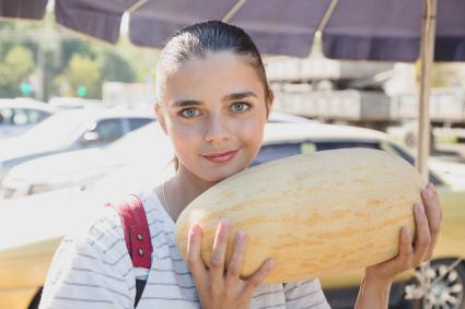 Челябинск. Девушка выбирает дыни на рынке.