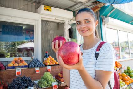 Челябинск. Девушка выбирает гранаты на рынке.