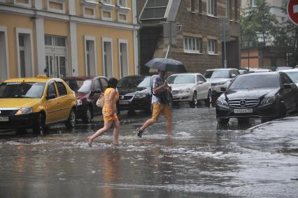 Москва. Мужчина и женщина переходят затопленную улицу.