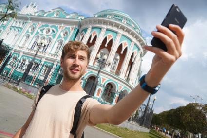 Екатеринбург. Мужчина фотографируется на фоне дома Севастьянова - достопримечательность города, где размещается резиденция губернатора Свердловской области. Внесен в список на голозование за символ города, для размещения на новых банкнотах 200 и 2000 рублей