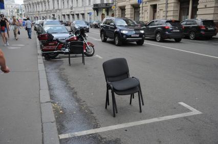 Москва. Парковочное место на улице Ильинка, огороженное офисными стульями.