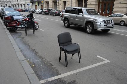 Москва. Парковочное место на улице Ильинка, огороженное офисными стульями.