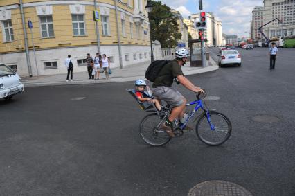 Москва.  Мужчина везет ребенка на велосипеде по Моховой улице.