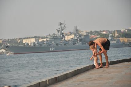 Крым, Севастополь. Мужчина с ребенком наблюдают за гвардейским ракетным крейсером `Москва`.