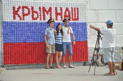 Крым, Севастополь. Молодые люди фотографируются на фоне флага РФ.