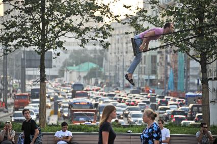 Москва.  Мужчина качается на качелях на Триумфальной площади.