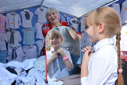 Новосибирск.  Девочка выбирает блузку на школьном базаре.