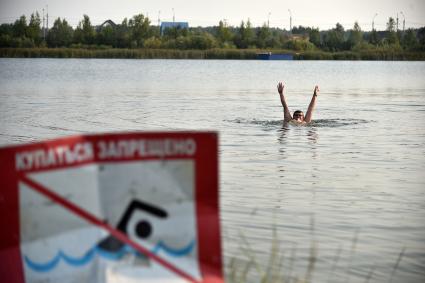 Новосибирск. Мужчина купается в озере возле знака `Купаться запрещено`.