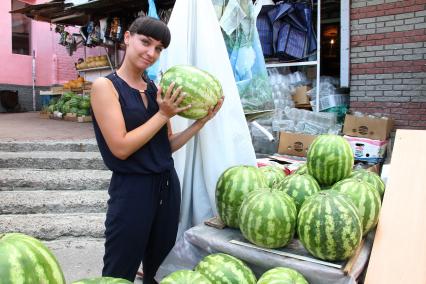 Нижний Новгород. Девушка выбирает арбуз на рынке .