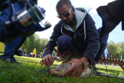 Екатеринбург. Мужчина достает пойманную рыбу (карп)на фестивале семейной рыбалки