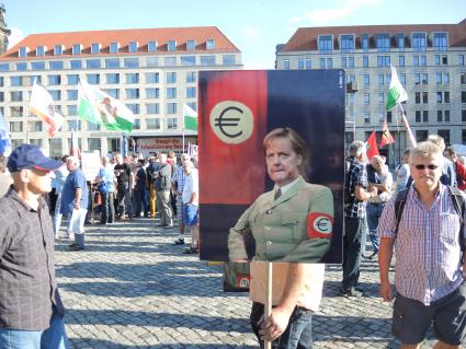 Германия,Дрезден. Митингующие с плакатом Ангелы Меркель на улице  города.